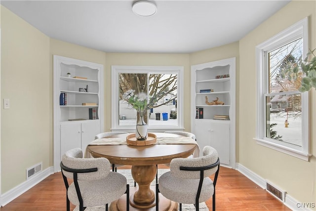 dining room with built in shelves and light hardwood / wood-style flooring