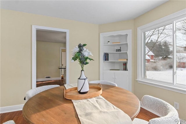 dining space featuring wood-type flooring and built in features