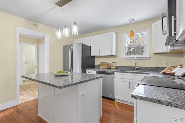 kitchen with stainless steel appliances, white cabinetry, a kitchen island, and sink