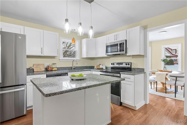 kitchen with sink, a center island, appliances with stainless steel finishes, light hardwood / wood-style floors, and white cabinets