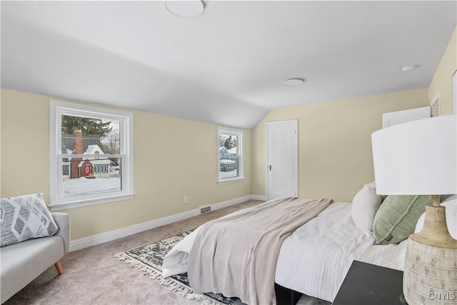 bedroom featuring multiple windows, lofted ceiling, and carpet floors