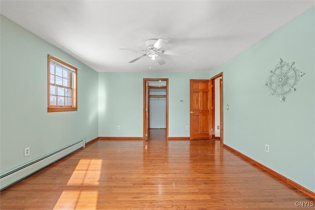 unfurnished room with ceiling fan, light wood-type flooring, and a baseboard heating unit