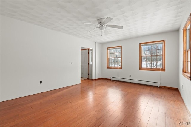 unfurnished room featuring ceiling fan, light wood-type flooring, a textured ceiling, and a baseboard heating unit