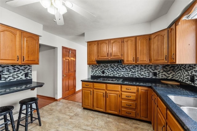 kitchen with ventilation hood, stainless steel gas cooktop, sink, and backsplash