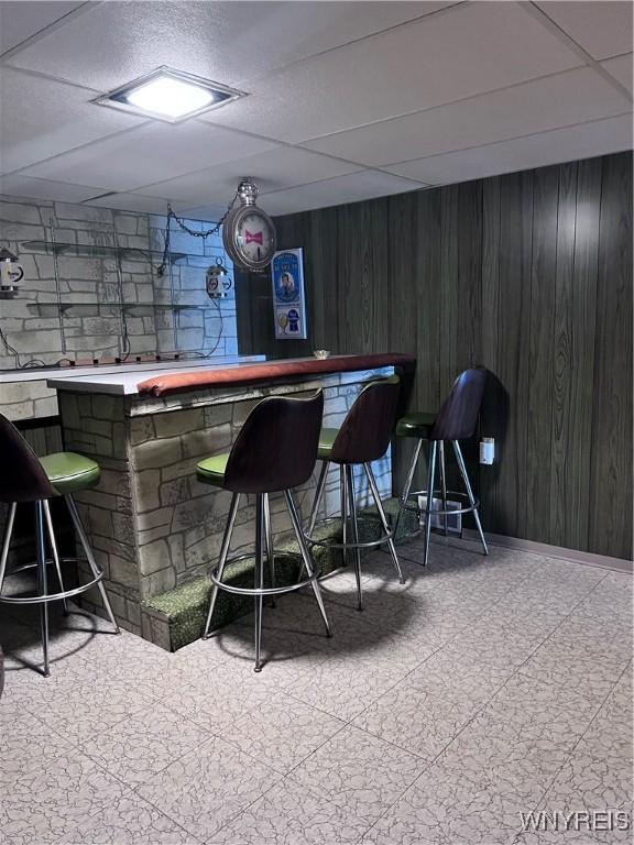 bar with a paneled ceiling and wood walls