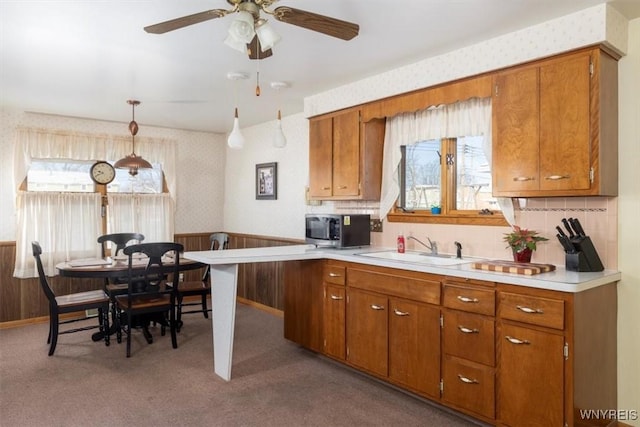 kitchen with pendant lighting, light colored carpet, ceiling fan, and sink