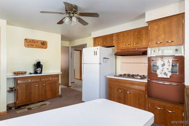 kitchen with white refrigerator, ceiling fan, stainless steel gas cooktop, and decorative backsplash