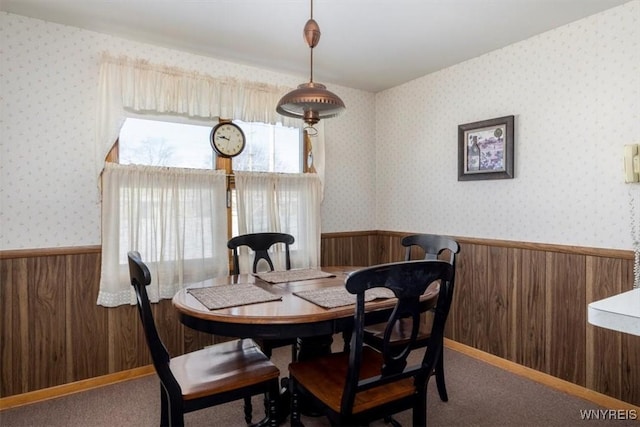 dining space with wooden walls and carpet flooring