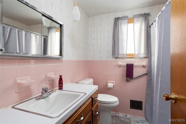 bathroom with vanity, tile walls, and toilet