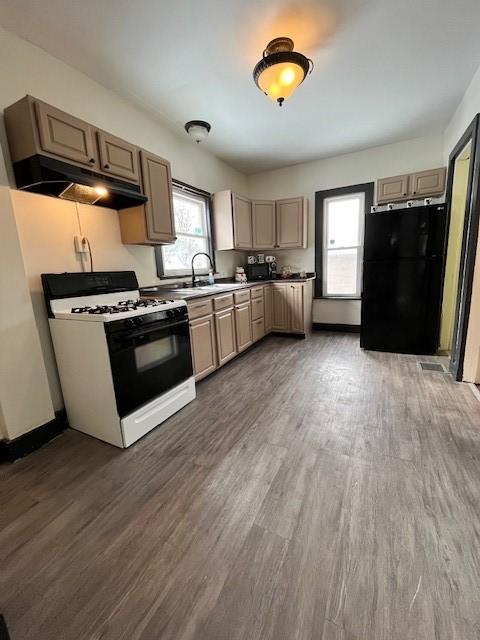 kitchen with black refrigerator, sink, range with gas cooktop, and dark hardwood / wood-style floors