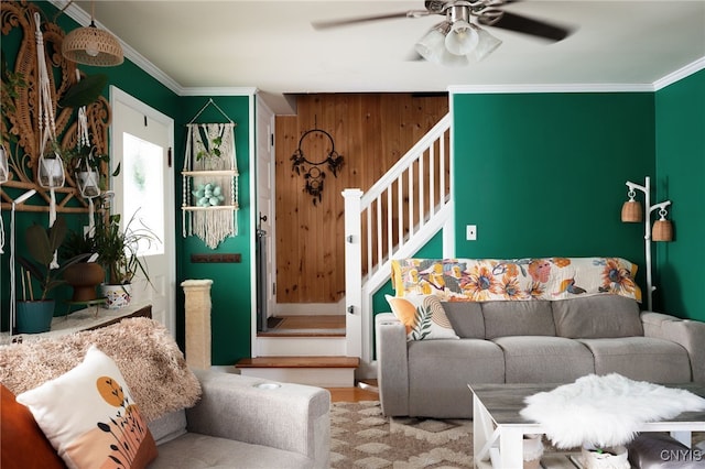 living room with crown molding, ceiling fan, and wooden walls