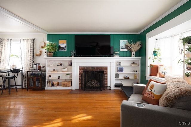 living room featuring a fireplace, ornamental molding, and wood-type flooring