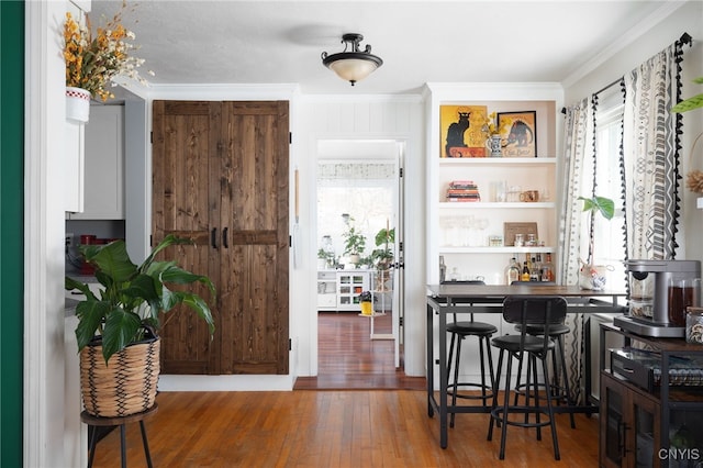 bar with hardwood / wood-style floors and ornamental molding