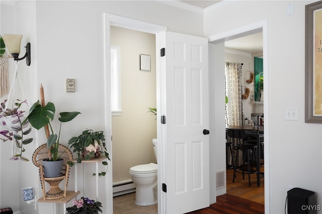 bathroom with crown molding, hardwood / wood-style flooring, toilet, and baseboard heating