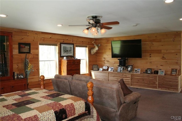 carpeted living room with ceiling fan and wood walls