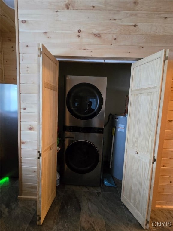 laundry room with wooden walls, stacked washing maching and dryer, and water heater