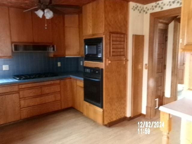 kitchen featuring tasteful backsplash, light hardwood / wood-style flooring, ceiling fan, range hood, and black appliances