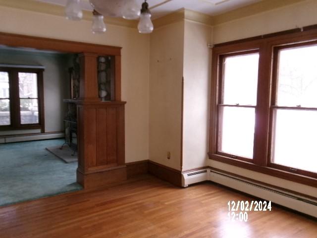 empty room with a baseboard heating unit and light hardwood / wood-style flooring