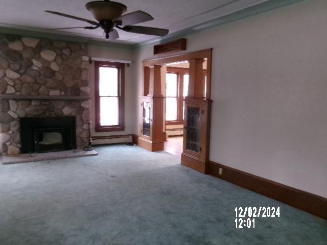 unfurnished living room with a fireplace, a baseboard radiator, carpet floors, ceiling fan, and crown molding