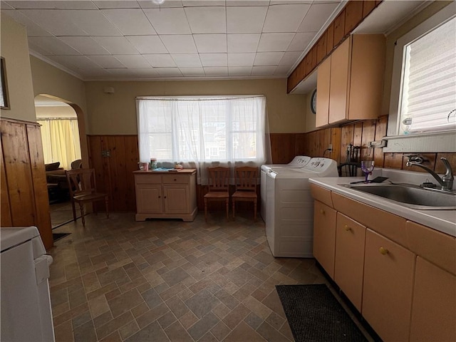 laundry room featuring separate washer and dryer, sink, crown molding, and wood walls