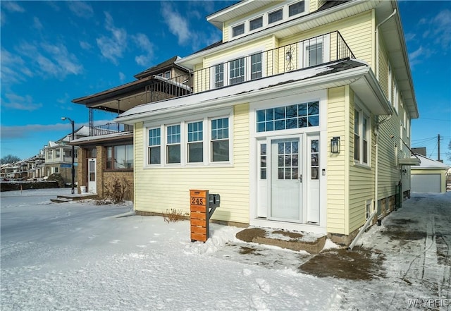 snow covered back of property with a balcony