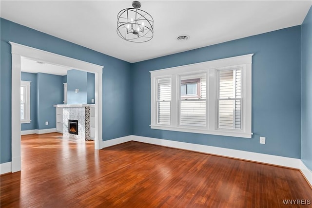 unfurnished living room with wood-type flooring and a notable chandelier