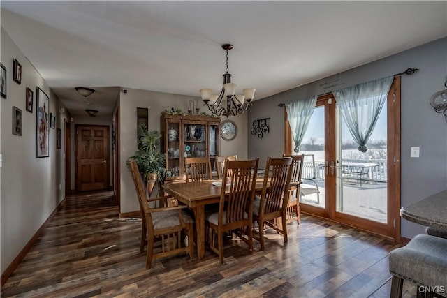 dining space featuring dark wood-type flooring, an inviting chandelier, and french doors