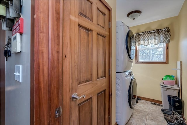 laundry area featuring light tile patterned flooring and stacked washing maching and dryer