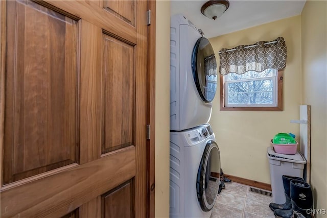 laundry area featuring stacked washing maching and dryer and light tile patterned floors