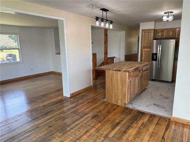 kitchen with decorative light fixtures, a center island, stainless steel fridge with ice dispenser, and hardwood / wood-style floors