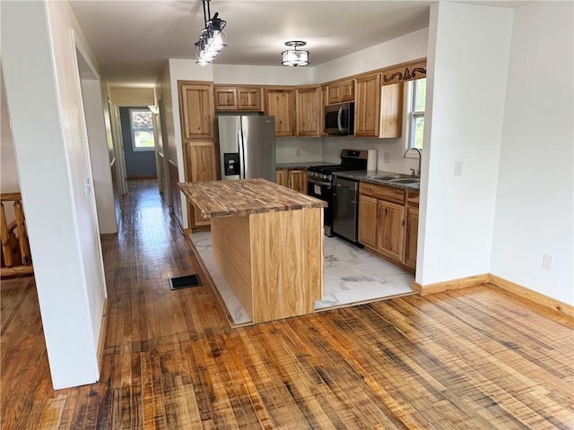 kitchen featuring sink, a center island, light hardwood / wood-style flooring, pendant lighting, and stainless steel appliances