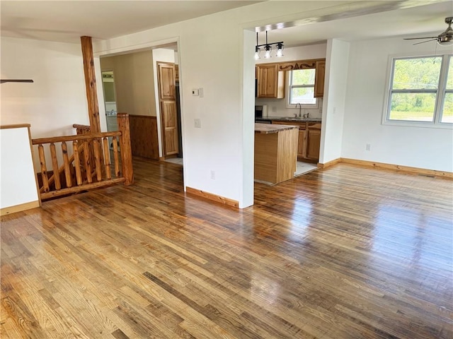 unfurnished living room with ceiling fan, light hardwood / wood-style flooring, sink, and a healthy amount of sunlight