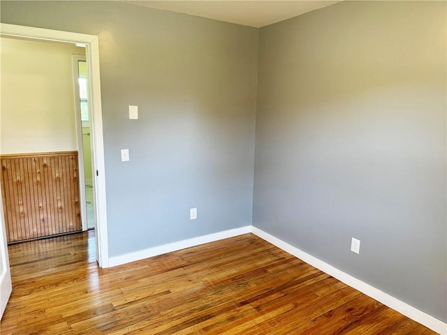 empty room with wooden walls and light hardwood / wood-style floors