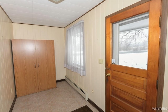 entryway with a healthy amount of sunlight, baseboard heating, and wood walls