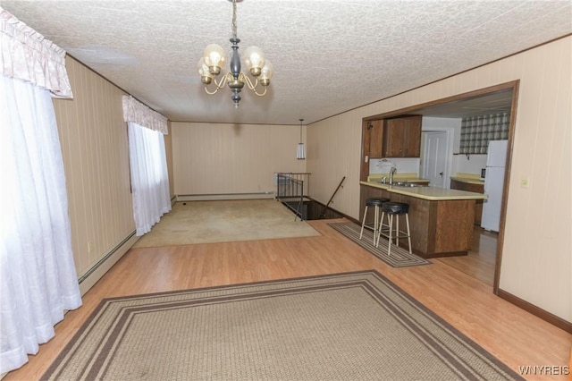 interior space featuring a baseboard radiator, sink, a textured ceiling, and light wood-type flooring