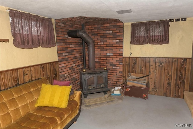 living room featuring wooden walls and a wood stove