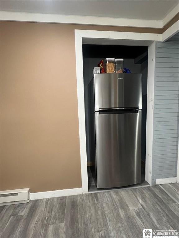 interior space featuring a baseboard heating unit, wood-type flooring, and stainless steel refrigerator