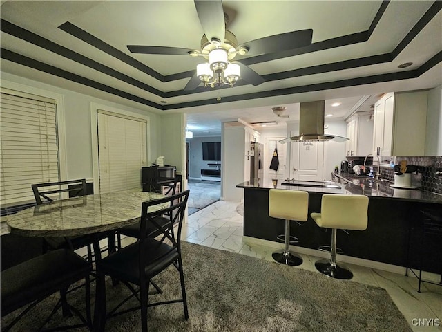 dining area featuring ceiling fan and a raised ceiling