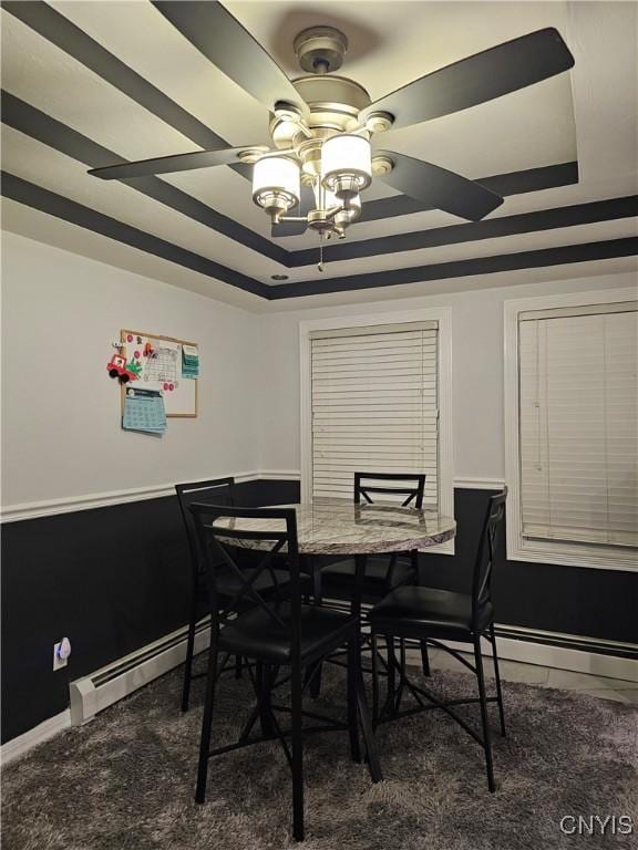 dining room with a tray ceiling, ceiling fan, and baseboard heating