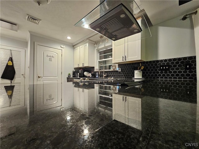 kitchen featuring tasteful backsplash, ornamental molding, white cabinets, dark stone counters, and exhaust hood