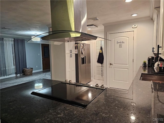 kitchen with stainless steel refrigerator with ice dispenser, crown molding, island range hood, dark stone countertops, and black stovetop