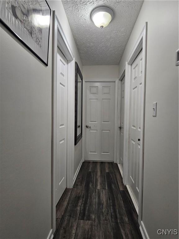 hallway with dark hardwood / wood-style floors and a textured ceiling