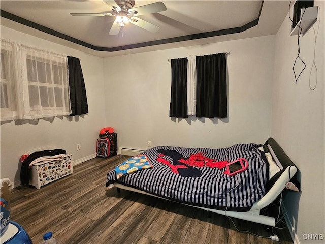 bedroom featuring a baseboard radiator, wood-type flooring, ceiling fan, and a tray ceiling