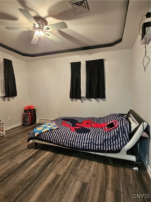 bedroom featuring hardwood / wood-style flooring, a raised ceiling, ceiling fan, and baseboard heating