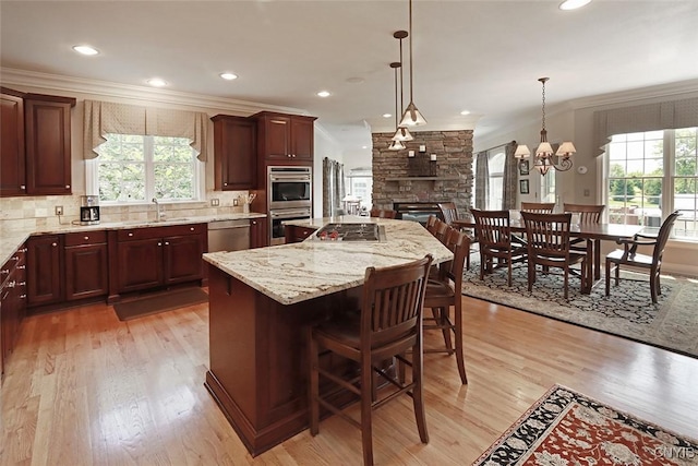 kitchen with a kitchen bar, ornamental molding, appliances with stainless steel finishes, pendant lighting, and a large island