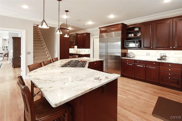 kitchen with appliances with stainless steel finishes, decorative light fixtures, a kitchen breakfast bar, decorative backsplash, and a center island