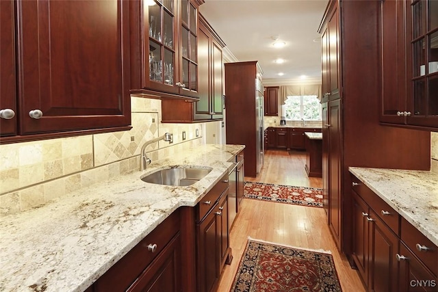 kitchen with sink, crown molding, backsplash, light hardwood / wood-style floors, and light stone countertops