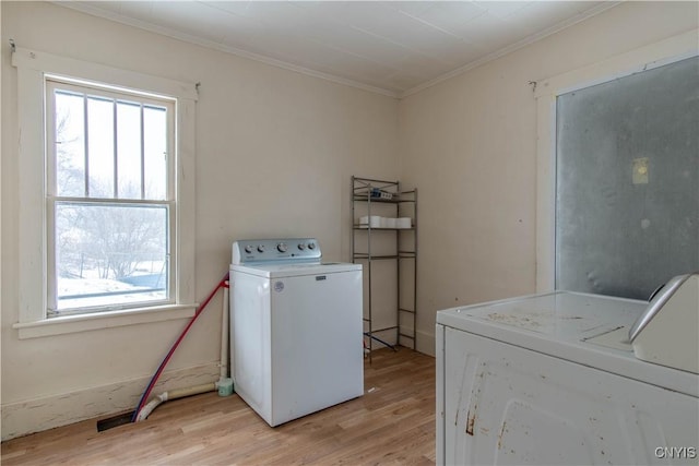 clothes washing area with washing machine and clothes dryer, ornamental molding, and light hardwood / wood-style floors