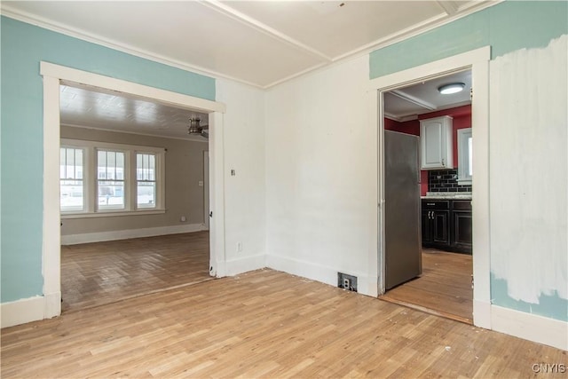 unfurnished room featuring ornamental molding and light wood-type flooring