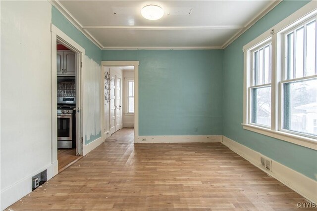 spare room with ornamental molding and light hardwood / wood-style floors